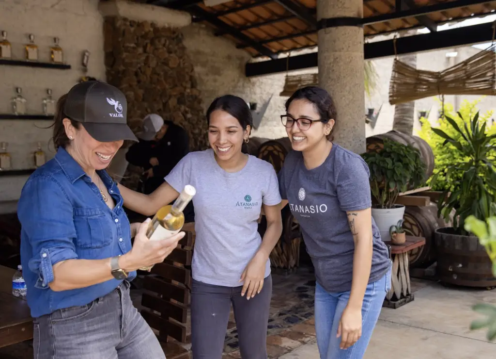 Image of women at Atanasio Distillery all gathered around a bottle of valor